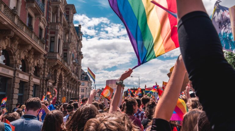 a crowd of people holding a rainbow flag